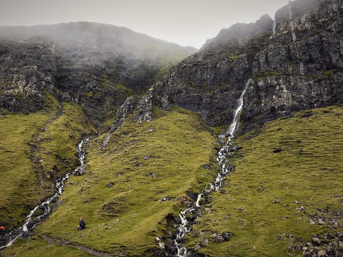 people walking on green grass field near waterfalls during daytime