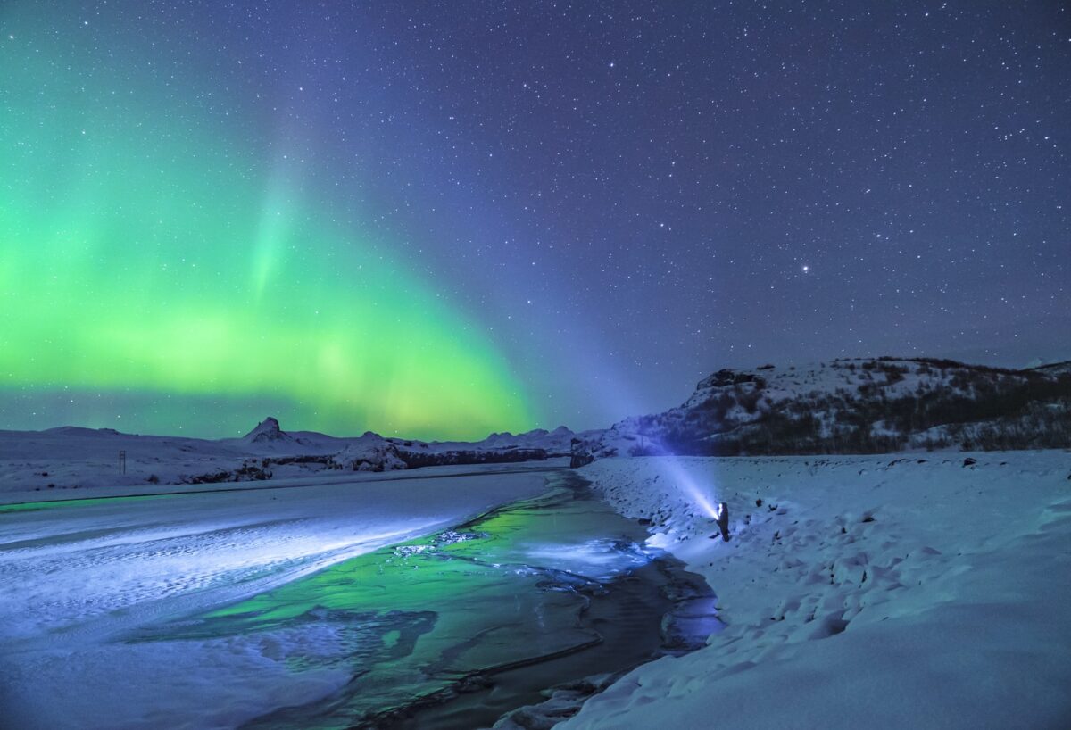 person standing under aurora lights
